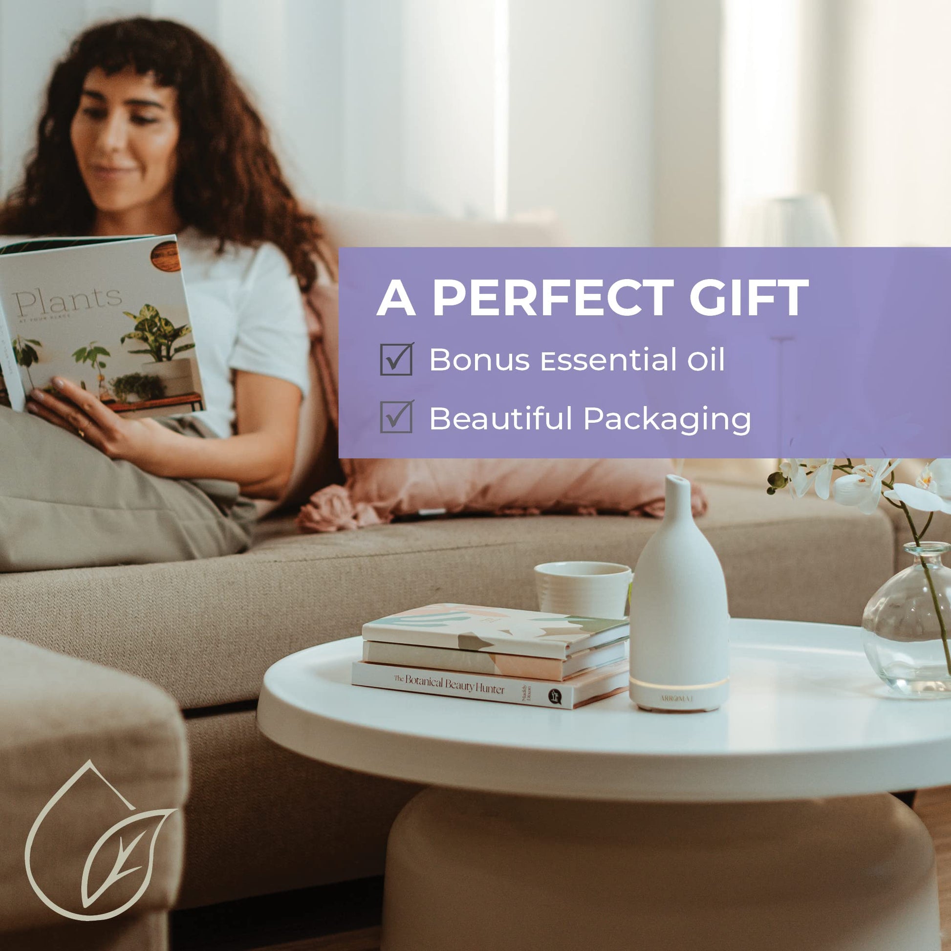a lady reading a book on a couch with a ceramic essential oil diffuser being used on a coffee table. text overlay saying perfect gift, bonus essential oil, beautiful packaging
